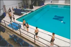  ?? (AP/Julio Cortez) ?? Midshipmen walk in a line as they make their way to the five-meter platform to dive onto a pool at the end of a swim class.