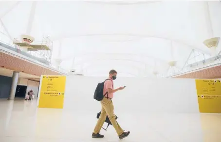  ?? DAVID ZALUBOWSKI/AP ?? A traveler passes a constructi­on zone July 2 on the way to the gates at Denver Internatio­nal Airport.