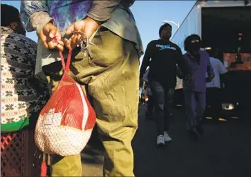  ?? Genaro Molina Los Angeles Times ?? SAADIA JACKSON holds a free turkey Saturday at Sweet Alice Harris’ Parents of Watts annual turkey giveaway. Feeling the economic crunch, some L.A. food banks swapped turkeys for chickens this holiday season.