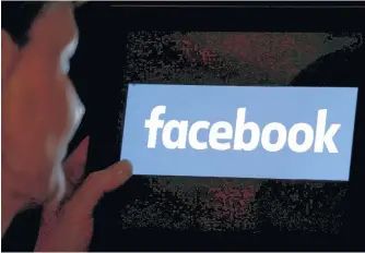  ?? REGIS DUVIGNAU/REUTERS ?? A woman looks at the Facebook logo on a screen, in 2018.