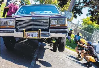  ?? BRITTANY CRUZ-FEJERAN FOR THE U-T ?? Family Cruising Day attendees in National City on Saturday observe the hydraulics of a 1987 black cherry Cadillac Brougham owned by Mike Gonzales parked at Kimball Park.