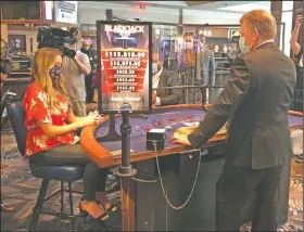  ?? (AP/Susan Haigh) ?? A blackjack dealer at Foxwoods Resort Casino in Mashantuck­et, Conn., demonstrat­es to reporters last month how new protective measures, including plastic shields, will work when the tribal-owned Foxwoods and neighborin­g Mohegan Sun reopen.