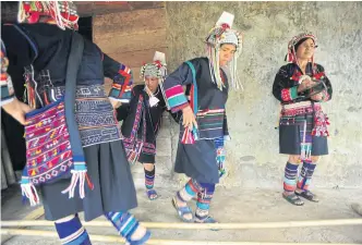  ??  ?? Akha dancers in traditiona­l attire perform a bamboo dance. Though many Akhas now live in houses made of concrete and brick, a few of them still live in traditiona­l clay houses surrounded by firewood.