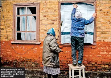  ?? ?? Elderly women placard a plastic sheet over a broken window after shelling near Bakhmut. (AFP)