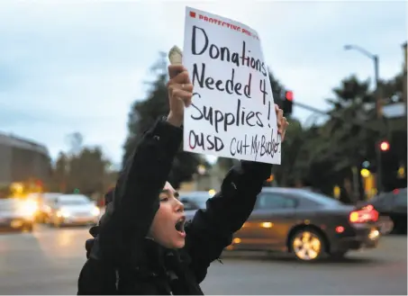  ?? Leah Millis / The Chronicle ?? Teacher Roxana Miles grips a sign and a donation she got for supplies at a protest against budget cuts for Oakland schools.