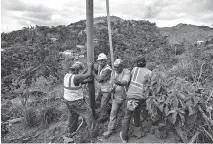  ?? AP Photo/Carlos Giusti ?? ■ Public Works Sub-Director Ramon Mendez, wearing a hard hat, directs locals who are municipal workers as they install a power pole Jan. 31 in an effort to return electricit­y to a home, four months after Hurricane Maria struck in Coamo, Puerto Rico. As...