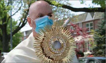  ?? (The New York Times/James Estrin) ?? The Rev. Peter Purpura carries a monstrance during his procession in the Middle Village neighborho­od of Queens on Sunday. After recovering from the coronaviru­s, Purpura found a way to bring the church directly to his people.