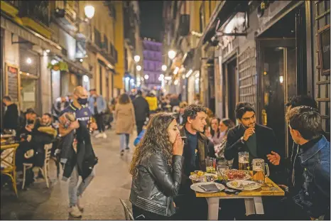  ?? (AP/Bernat Armangue) ?? Tourists and locals have drinks at a bar in downtown Madrid, Spain. With its policy of open bars and restaurant­s — indoors and outdoors — and by keeping museums and theaters running, Madrid has built a positive reputation with European travelers amid the pandemic.