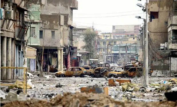  ?? —Photos by Reuters ?? A completely destroyed street in Mosul with burnt cars and buildings after clashes between Iraqi forces and Daesh in March this year.