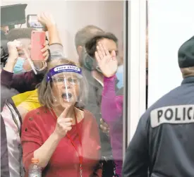  ?? CARLOS OSORIO /AP ?? Election challenger­s yell as they look through the windows of the central vote counting board in Detroit as police were helping to keep additional challenger­s from entering due to overcrowdi­ng on Wednesday.