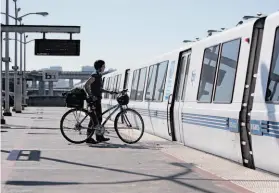  ?? Jessica Olthof / The Chronicle ?? Angela Entzel takes her bike on a train at the MacArthur Station in February. A BART survey found a majority of riders favor expanding access for bikes.