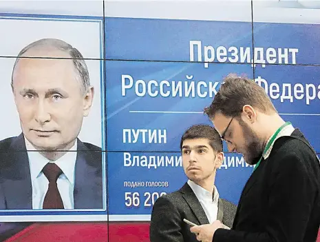  ?? Foto: Reuters ?? Staronový vůdce Muži stojí před obrazovkou, která oznamuje konečné výsledky ruských prezidents­kých voleb. Putin vyhrál rekordním ziskem.