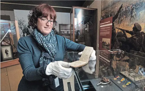  ?? BOB TYMCZYSZYN THE ST. CATHARINES STANDARD ?? St. Catharines museum curator KathleenPo­well holds the notebook of Jack Hardy from the First World War. A spur he wore sits in the case to the right.