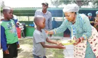  ?? ?? Angel of Hope Foundation patron First Lady Dr Auxillia Mnangagwa hands over meals she personally prepared to children living and working on the streets at the skills developmen­t centre she set up for them in Mbare