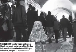  ?? AP/MAYA Alleruzzo ?? A Palestinia­n toddler wears a jilbab, an islamic garment, on the eve of the Muslim holy month of Ramadan in the Old City of Jerusalem, on April 12.