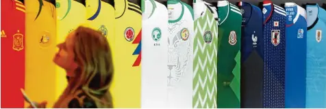  ?? Foto: Kyodo, dpa ?? Bunte Mischung: Eine Frau begutachte­t die aktuellen Trikots der WM Teilnehmer.