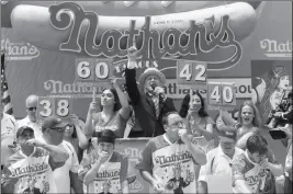  ?? ASSOCIATED PRESS ?? MASTER OF CEREMONY GEORGE SHEA (top center) announces that reigning champion Joey Chestnut (bottom center) is winning the men’s competitio­n of the Nathan’s Famous Fourth of July hot dog eating contest in the final seconds of the competitio­n Wednesday in New York’s Coney Island. Chestnut broke his own world record by eating 74 hot dogs in 10 minutes.