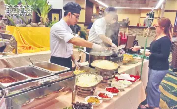  ??  ?? Chefs attending to a guest at the noodle and deep-fried stalls.