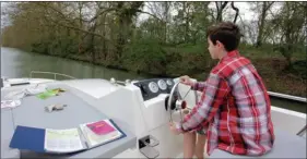  ??  ?? Lucien, jeune apprenti mousse de douze ans, attentif à la barre d’un bateau fluvial sur le canal du Midi. C’est le bon âge pour apprendre à tenir un cap.