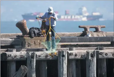  ?? KARL MONDON — STAFF PHOTOGRAPH­ER ?? A crab fisherman checks his trap while fishing off of Torpedo Wharf inside the Golden Gate in San Francisco on Monday. A threeyear scientific study found trillions of “microplast­ic” pieces are flowing into San Francisco Bay, threatenin­g the ecosystem.