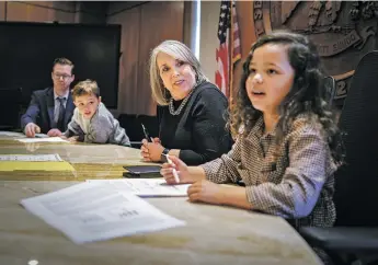  ?? GABRIELA CAMPOS/THE NEW MEXICAN ?? Gov. Michelle Lujan Grisham is joined Thursday by her grandchild­ren, Avery Stuart and Mason Stuart, before signing House Bill 130, which will mandate an increase in learning time in public schools to 1,140 hours plus additional profession­al developmen­t time for teachers. The governor was helping take care of her grandchild­ren for the day as they were on spring break.