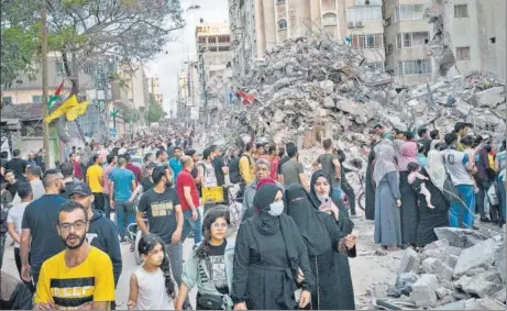  ?? AP ?? People pass the rubble from a building previously destroyed in an airstrike in Gaza City on Friday.