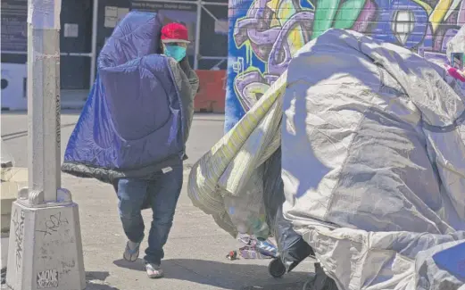  ?? SETH WENIG/AP ?? Sotero Cirilo airs out a sleeping bag at the homeless encampment where he sleeps in Queens. The 55-year-old immigrant from Mexico used to make $800 a week at two Manhattan restaurant­s, which closed when the COVID-19 pandemic started, and he ended up homeless.