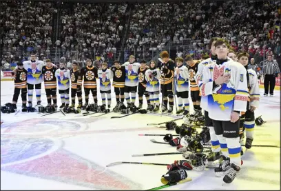  ?? JACQUES BOISSINOT — THE CANADIAN PRESS VIA AP ?? Ukraine and Boston Junior Bruins peewee teams stand together during the national anthems before a game on Saturday at the Internatio­nal Peewee Hockey tournament in Quebec City.