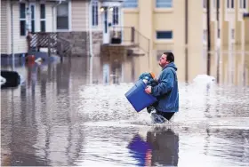  ?? ROBERT FRANKLIN/ASSOCIATED PRESS ?? Roget Willemin carries belongings out of his flooded home in South Bend, Wednesday. States of emergency were declared across the Midwest. Ind.,