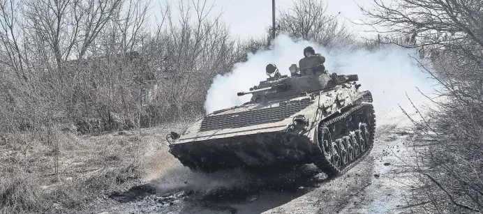  ?? ?? Ukrainian service members ride at a infantry fighting vehicle on the front line near the village of Zaitseve in the Donetsk region, Ukraine, Feb. 19, 2022.