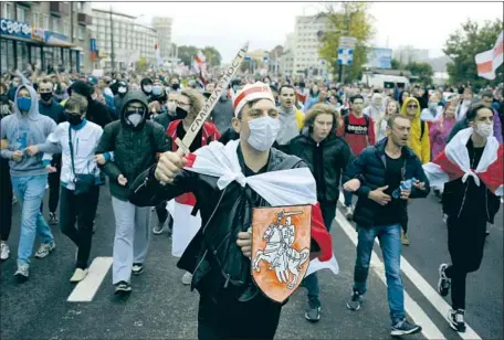  ?? DEMONSTRAT­ORS, Associated Press ?? including one wearing an old Belarusian f lag and bearing a cardboard sword with the word “solidarity,” march Sunday in Minsk, Belarus, to protest the presidenti­al election results. President Alexander Lukashenko has defied calls for him to leave off ice.