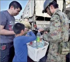  ??  ?? A Self-Defence Forces personnel helps a family to pack bottles of water in Mashiki, Kumamoto prefecture. — AFP photo