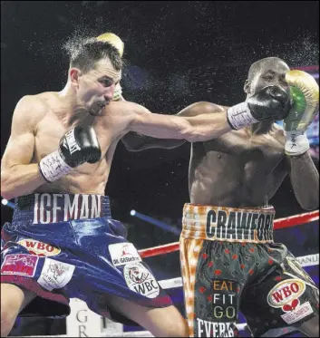  ??  ?? Terence Crawford, right, blocks a punch by Viktor Postol during their WBO/WBC junior welterweig­ht title unificatio­n fight Saturday night at the MGM Grand Garden.