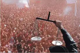  ?? ASSOCIATED PRESS FILE PHOTO ?? In this Jan. 26, 2013, photo, an Egyptian fan of the Al-Ahly soccer club displays scales to fans celebratin­g a court verdict that returned 21 death penalties in 2012 soccer violence against their supporters in Port Said, in Cairo, Egypt.