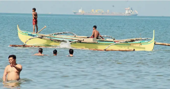  ?? PHOTOGRAPH BY BOB DUNGO JR. FOR THE DAILY TRIBUNE @tribunephl_bob ?? Summer cooldown
Several men take a dip in Cavite Saturday, 25 March 2023, to beat the summer heat as two fishermen set forth for deeper water for the day’s catch.