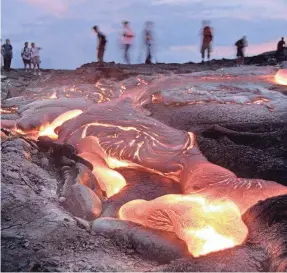  ?? USA TODAY FILE ?? Visitors to Hawaii Volcanoes National Park view a surface flow of lava from the Pu'u O'o vent on the slope of the Kilauea caldera, which began erupting in 1983. It is a three-mile round trip hike over fresh lava fields (no paved trail) to get to this flow at the end of Chain of Craters Road.