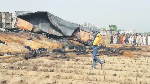  ?? — AFP photo ?? Local residents look at burnt bodies following the oil tanker blast.