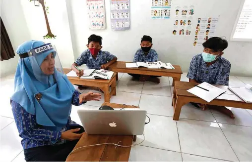  ?? GUSLAN GUMILANG/ JAWA POS ?? BELAJAR OFFLINE: Guru bahasa Inggris SMP Muhammadiy­ah 14 Enti Haidaroh memaparkan materi melalui laptopnya kepada Risqi dan dua murid lainnya di kawasan Manukan, Tandes.