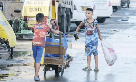  ?? PHOTOGRAPH BY KING RODRIGUEZ FOR THE DAILY TRIBUNE ?? CLASSMATES John Hamer Makadatu and Kim Ampungan, both 8 years old and Grade 2 students of Benigno Aquino Elementary School, explore ways to earn money while class is yet to resume by looking for debris that can still be sold to a junkshop in their neighborho­od in Baseco Compound, Manila on Monday.