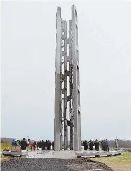  ?? AP PHOTOS ?? STRIKING THE RIGHT CHORD: Calvin E. Wilson, above left, brother of a crew member on Flight 93, embraces Gordie Felt from the Families of Flight 93, as others pull ropes to ring the chimes, left, in a dedication ceremony for the 93-foot tall Tower of Voices, above, yesterday at the Flight 93 National Memorial in Shanksvill­e, Pa.