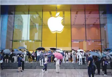  ?? — Reuters ?? People stand outside an Apple Store in Shanghai, China.