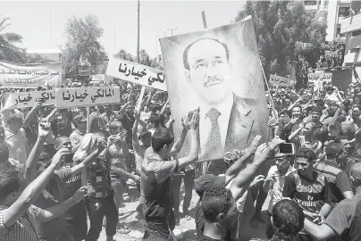  ?? AMER AL-SAEDI / AFP / GETTY IMAGES ?? Iraqis hold a giant portrait of Iraq’s Prime Minister Nuri al-Maliki during a demonstrat­ion to support him on Monday.