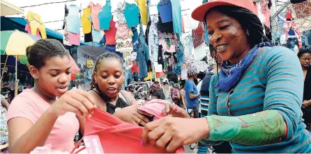  ?? RUDOLPH BROWN/PHOTOGRAPH­ER ?? Nadine is all smiles displaying fashionabl­e clothing to two customers – Michaela (left) and Georgiann.