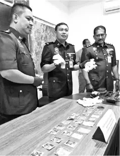  ??  ?? Haris (centre) showing the jewellery items and break-in tools seized from the suspects.