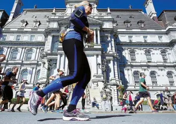  ?? PIERRE OBENDRAUF/MONTREAL GAZETTE ?? Runners pass Montreal city hall on Notre-Dame street during the Montreal Marathon.