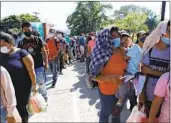  ?? DELMER MARTINEZ AP ?? Migrants who are part of a caravan hoping to reach the United States wait in a line to have their documents checked by police in Honduras on Saturday.