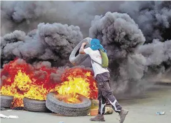  ??  ?? »Un hombre arroja una llanta a una barricada en llamas durante una jornada de protestas en Haití.