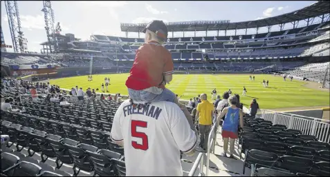  ?? JASON GETZ / SPECIAL ?? Fans Austin Swinehamer, 4, and his dad, David, of Bluffton S.C., head to their seats as the Atlanta Braves take the field in an exhibition game against the New York Yankees in the first game in SunTrust Park on Friday.