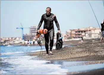  ?? ANDREW MEDICHINI/AP ?? Fisherman Federico Burresi walks along the beach Saturday in Ladispoli, a coastal town outside of Rome.