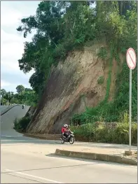  ?? SAPRI/SAMARINDA POS/JPG ?? Jawa Pos BAHAYA MENGANCAM: Pengendara motor melewati ruas jalanan di Miramar, Samarinda, yang tebing di sisi jalannya tergerus longsor. Sewaktu-waktu tebing bisa longsor dan mengancam pengguna jalan.